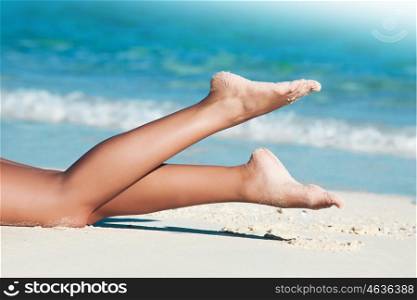 Woman laying by sea. Legs of young woman laying by tropical sea