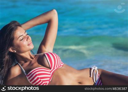 Woman laying by sea. Young woman in bikini laying by tropical sea