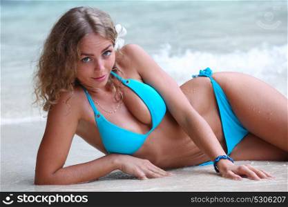 Woman laying by sea. Young woman in bikini laying by tropical sea