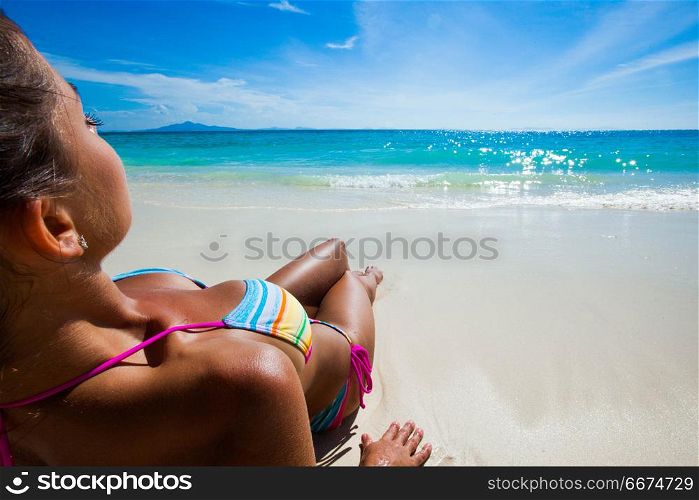 Woman laying by sea. Young woman in bikini laying on white sand by tropical sea