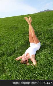 Woman laying down green field with legs up