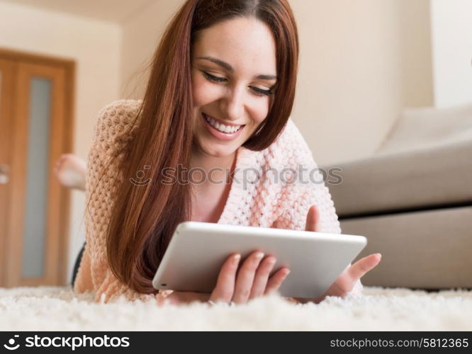 Woman laying down on carpet with a tablet