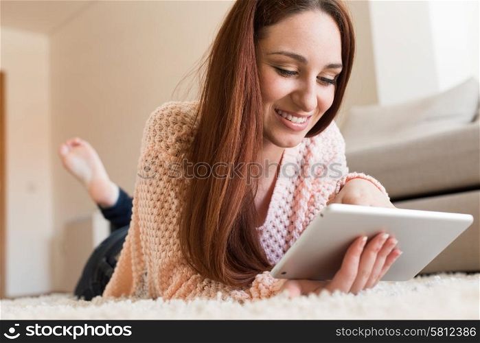 Woman laying down on carpet with a tablet