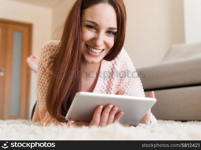 Woman laying down on carpet with a tablet