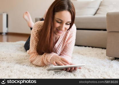 Woman laying down on carpet with a tablet