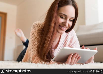 Woman laying down on carpet with a tablet