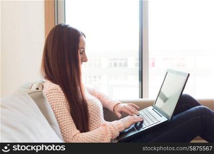 Woman laying down on couch with a laptop