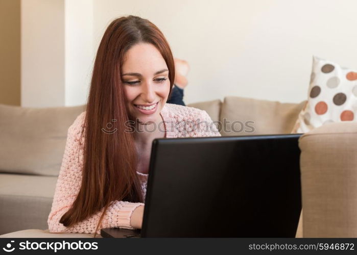 Woman laying down on couch with a laptop