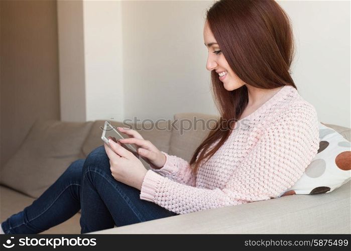 Woman laying down on couch with a tablet