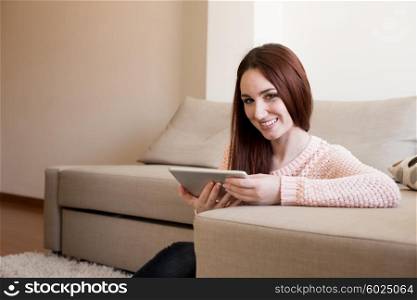 Woman laying down on couch with a tablet