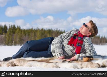 Woman laying down on the reindeer skin and enjoying the warm sun.