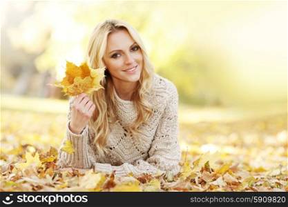 Woman laying in autumn park. Portrait of beautiful woman laying in autumn park with maple leaves