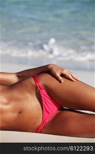 Woman laying on beach. Beautiful tan woman in swimwear laying on beach