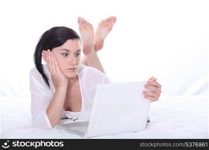 Woman laying on bed with laptop