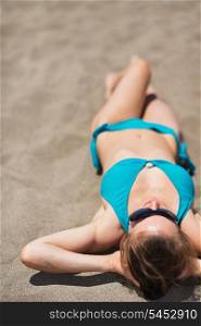 Woman laying on sand beach. Rear view