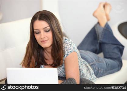 Woman laying on sofa with laptop