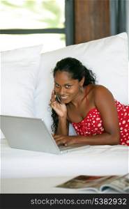 Woman laying on sofa with laptop and mobile