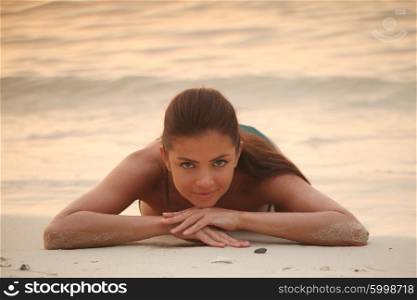 Woman lays on sand of beach . Beautiful woman lays on sand of beach in sunset