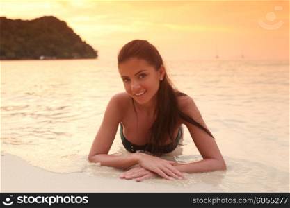 Woman lays on sand of beach . Beautiful woman lays on sand of beach in sunset