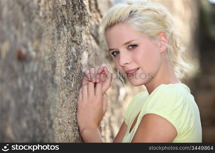 Woman leaning against old stone wall