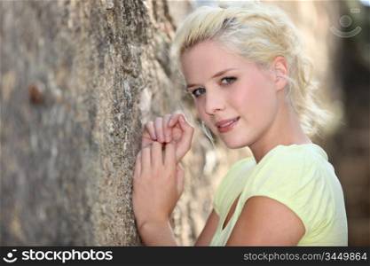 Woman leaning against old stone wall