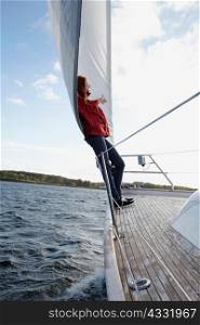 Woman leaning against sail on yacht