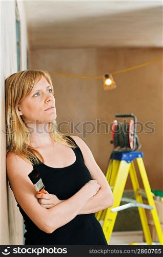 Woman Leaning Against Wall Holding Paintbrush