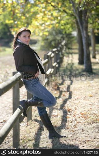 Woman leaning against wooden fence