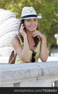 woman leaning on bridge and using mobile phone