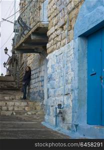 Woman leaning on stone wall in street, Safed, Northern District, Israel