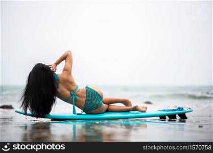 Woman Leaning On Surfboard At Beach Against Sky