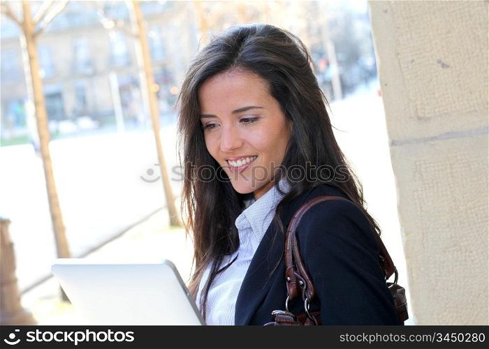 Woman leaning on wall in town with electronic tablet