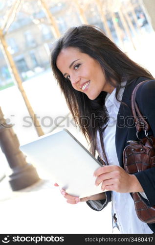 Woman leaning on wall in town with electronic tablet