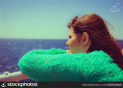 Woman leans on the railing and looking out to sea on the horizon