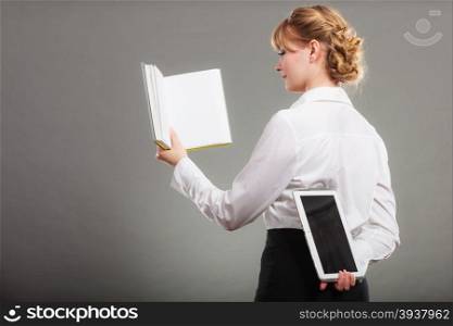 Woman learning with ebook and book. Education.. Woman learning with book holding ebook reader behind back. Choice between modern educational technology and traditional way method. Girl holding digital tablet pc and textbook. Contemporary education.