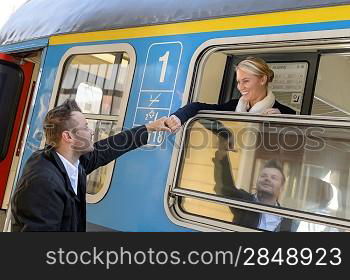 Woman leaving with train man holding hand goodbye smiling commuter