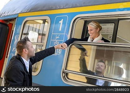 Woman leaving with train man holding hand goodbye smiling commuter