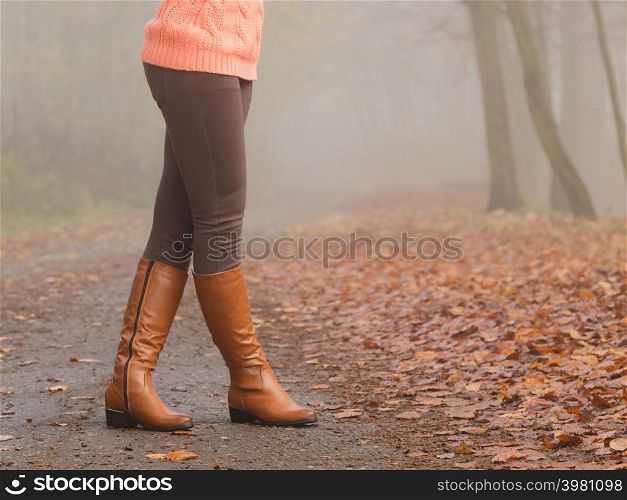 Woman legs in brown boots. Female in autumn park forest. Fall winter fashion.. Woman legs in brown boots. Fall fashion