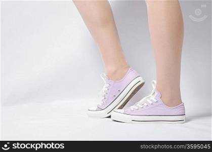 woman legs on white pink gumshoes on side view closeup