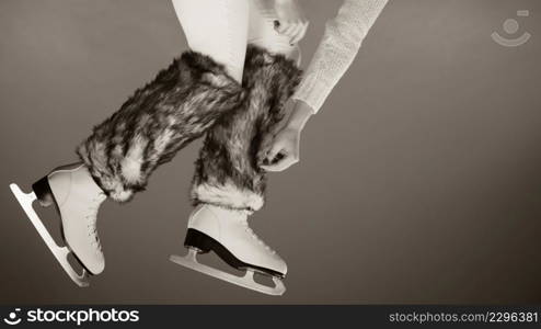 Woman legs wearing skates fur warm socks. Girl getting ready for ice skating. Winter sport activity. Studio shot b&w photo. Woman legs wearing ice skates fur socks, skating