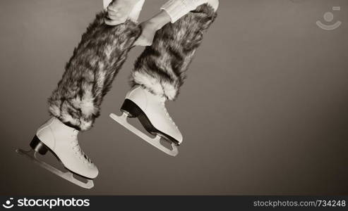 Woman legs wearing skates fur warm socks. Girl getting ready for ice skating. Winter sport activity. Studio shot b&w photo. Woman legs wearing ice skates fur socks, skating