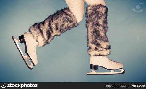 Woman legs wearing skates fur warm socks. Girl getting ready for ice skating. Winter sport activity. Studio shot on blue