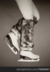 Woman legs wearing skates fur warm socks. Girl getting ready for ice skating. Winter sport activity. Studio shot b&amp;amp;w photo