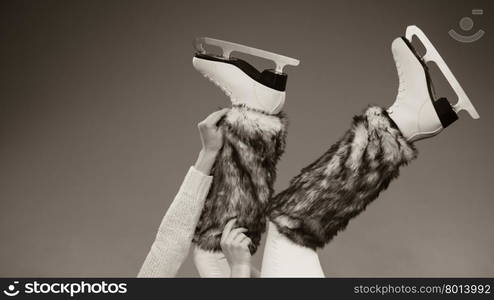 Woman legs wearing skates fur warm socks. Girl getting ready for ice skating. Winter sport activity. Studio shot b&amp;amp;w photo