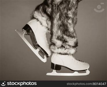 Woman legs wearing skates fur warm socks. Girl getting ready for ice skating. Winter sport activity. Studio shot b&amp;amp;w photo