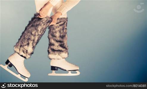 Woman legs wearing skates fur warm socks. Girl getting ready for ice skating. Winter sport activity. Studio shot on blue