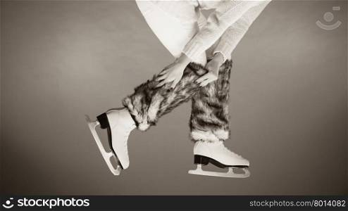 Woman legs wearing skates fur warm socks. Girl getting ready for ice skating. Winter sport activity. Studio shot b&amp;amp;w photo