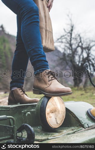 Woman legs with leather shoes in the forest. Truck