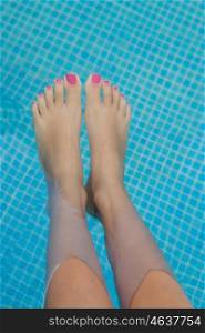 Woman legs with pink nail in swimming pool