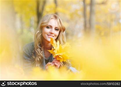 Woman lies in maple leaves . Young woman lies in maple leaves at autumn park
